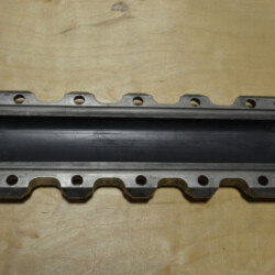 Metal gasket or sealing component with multiple bolt holes, designed for industrial machinery or automotive applications, displayed on a wooden surface