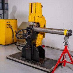 "Technician operating a hydraulic metal bending or pressing machine in a workshop."