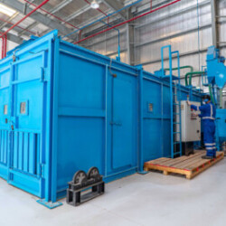 Large industrial processing unit with a technician operating the control panel in a factory environment