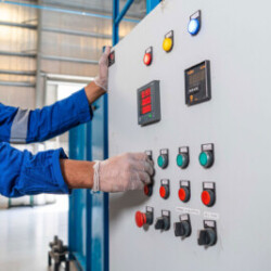 Technician operating an industrial control panel in a safety-compliant environment.