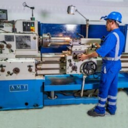 Technician operating a precision lathe machine in an industrial workshop