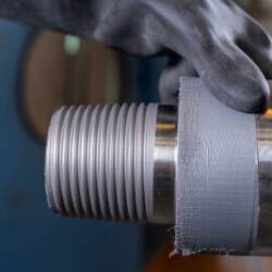 Close-up of a technician wearing protective gloves inspecting a metal component