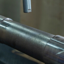 Close-up of a cylindrical metal workpiece undergoing precision machining.